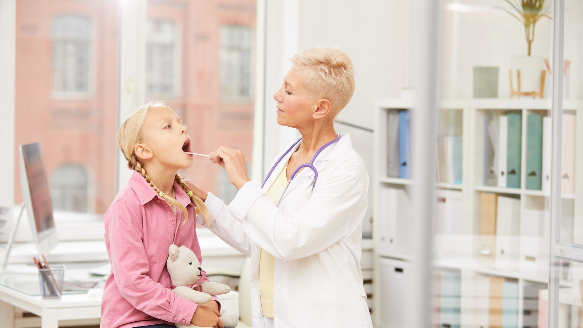 Pediatrician checking throat of youthful patient